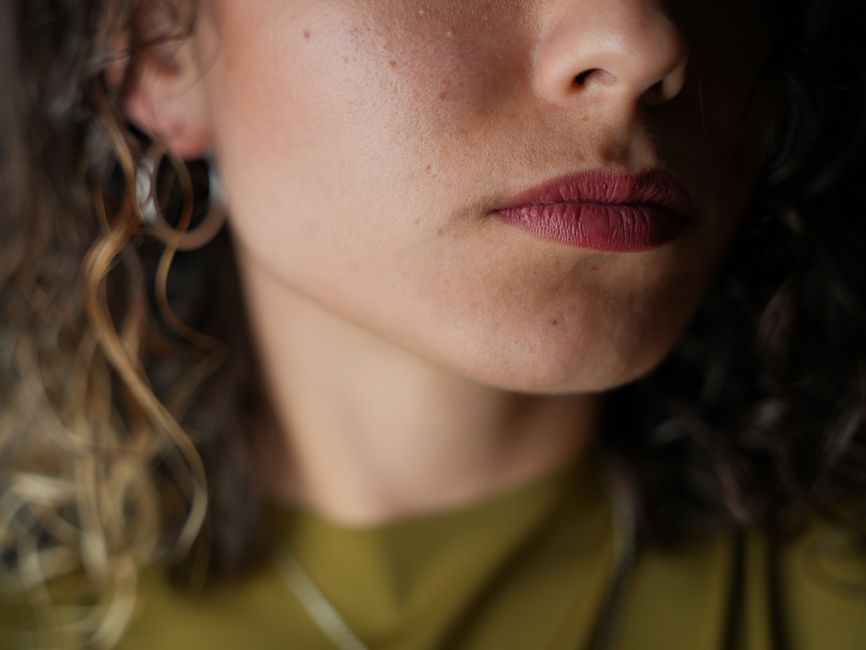 Artistic close-up portrait of a woman's lips and chin with bold lipstick.