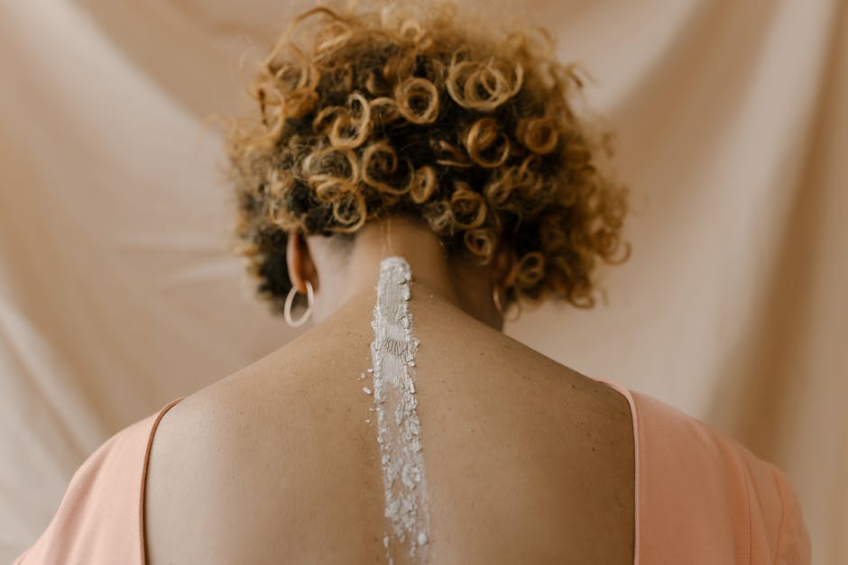 A woman with curly hair and clay on her back, captured in a studio setting.