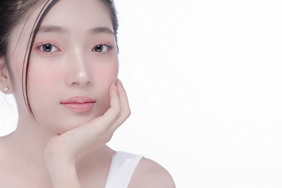 Close-up portrait of a young woman with clear skin in a studio setting, showcasing beauty and skincare.