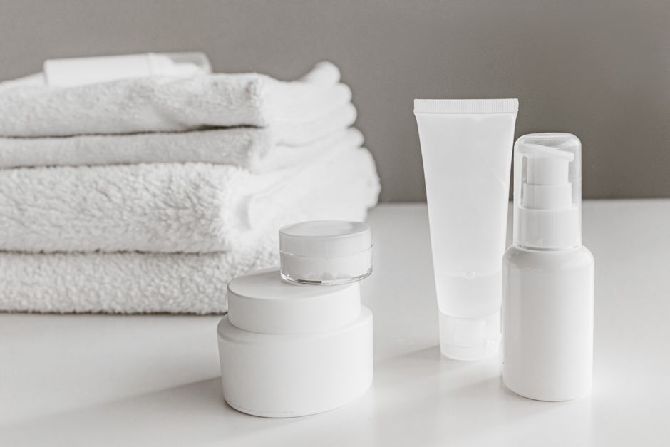 Minimalist arrangement of white skincare products and towels for a modern aesthetic.