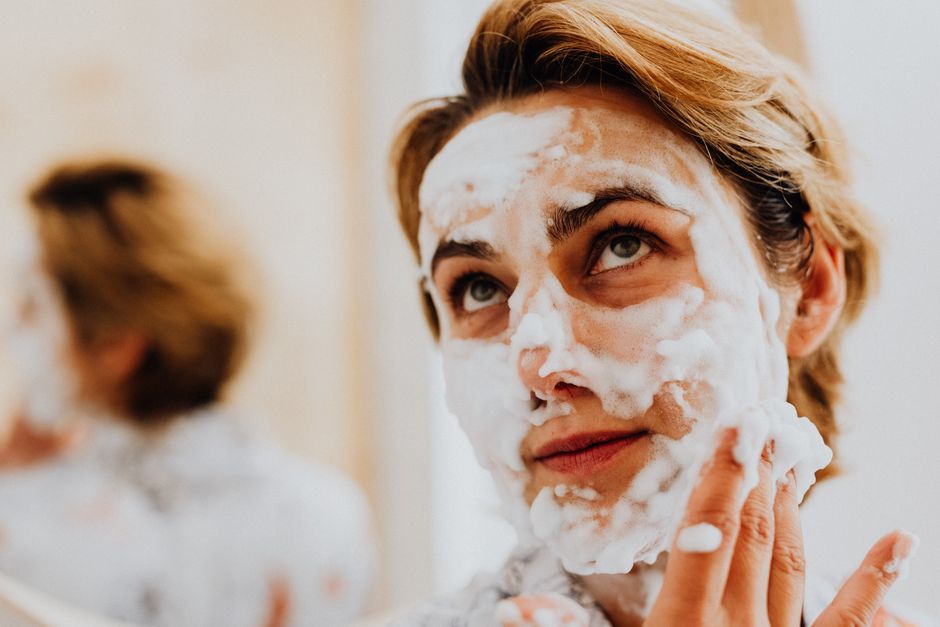 Close-up of a woman applying foaming cleanser for a refreshing skincare routine.