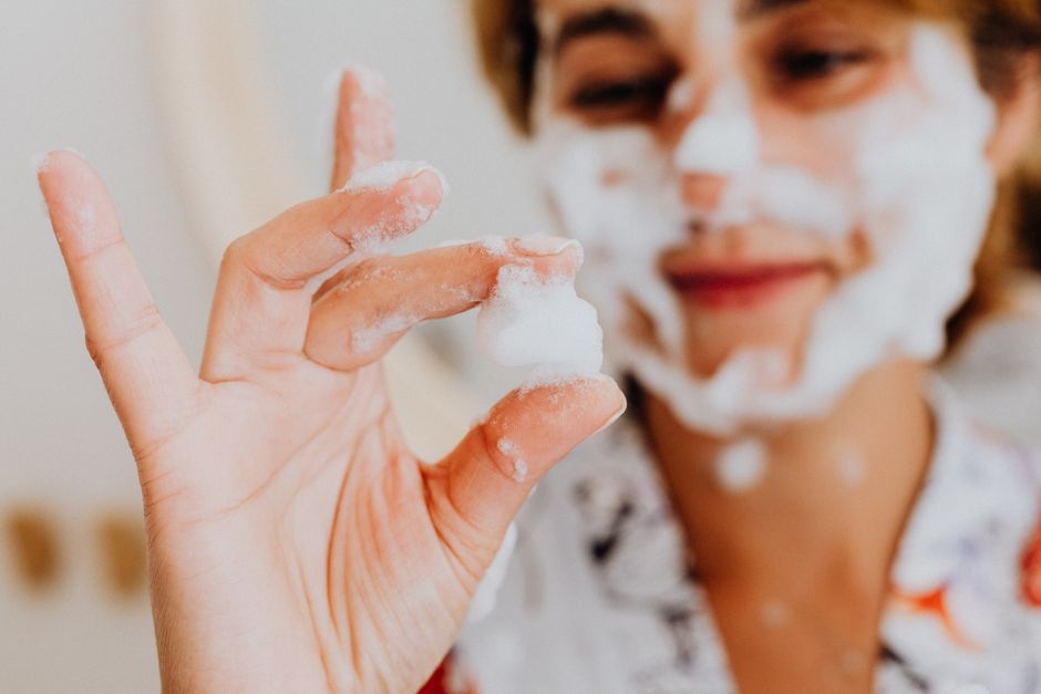 Close-up of a woman using face cleansing foam, showcasing skincare routine.