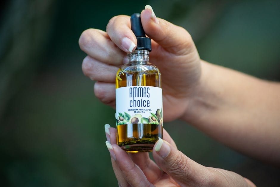 Close-up of hands holding a hair scalp oil bottle.