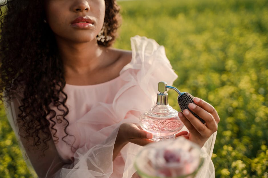 A woman with curly hair holding a vintage perfume bottle in a sunny flower field.