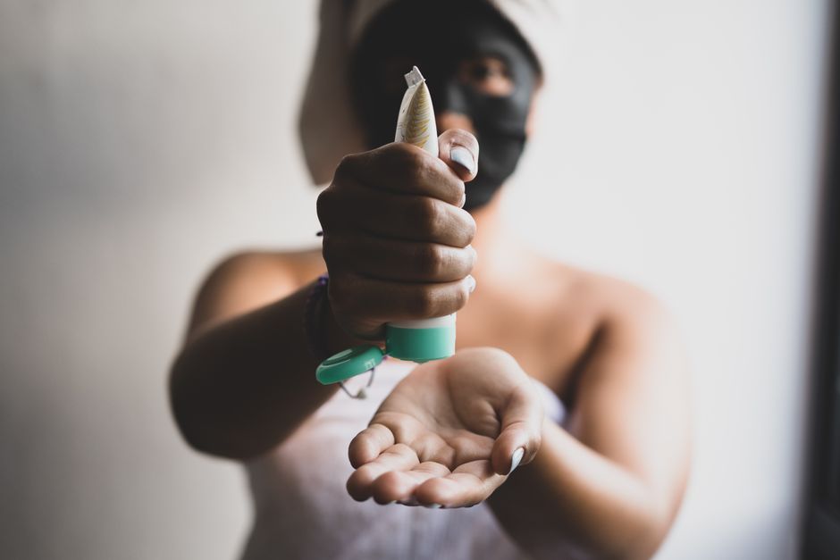 Close-up of a woman applying skincare cream with a blurred background, emphasizing a beauty routine.
