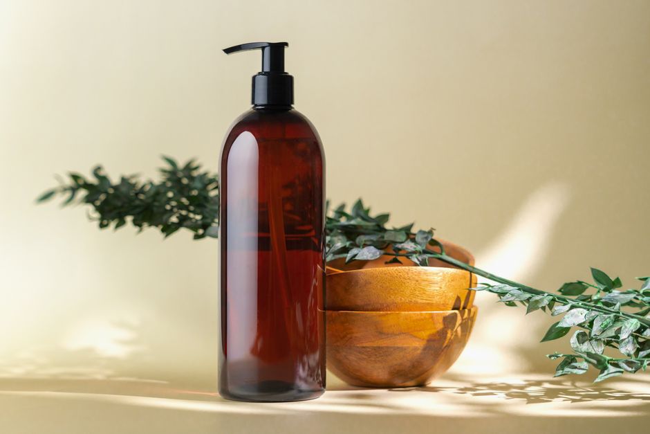 Elegant amber bottle beside wooden bowls and greenery, ideal for organic cosmetics or spa themes.