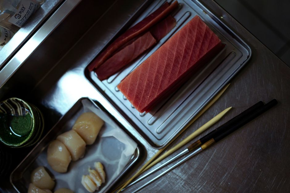 Top view of fresh tuna and scallops on stainless steel trays, ready for sushi preparation.