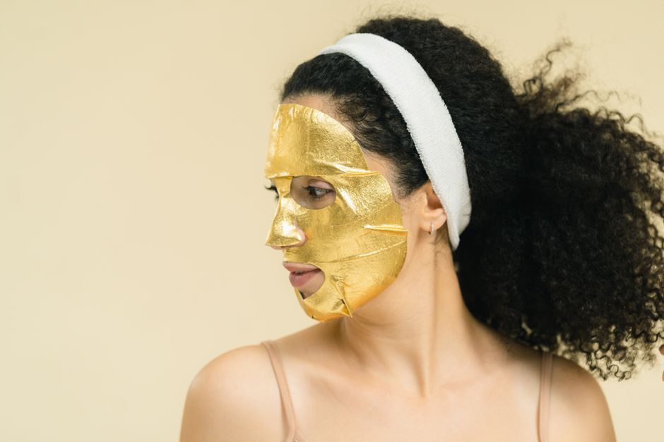 Woman in a gold facial mask for luxurious skincare and self-care routine.