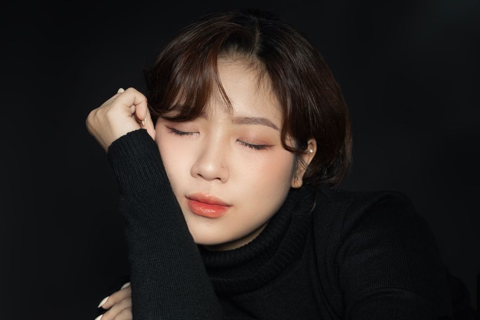 Tranquil portrait of a woman with closed eyes, clad in a black turtleneck.
