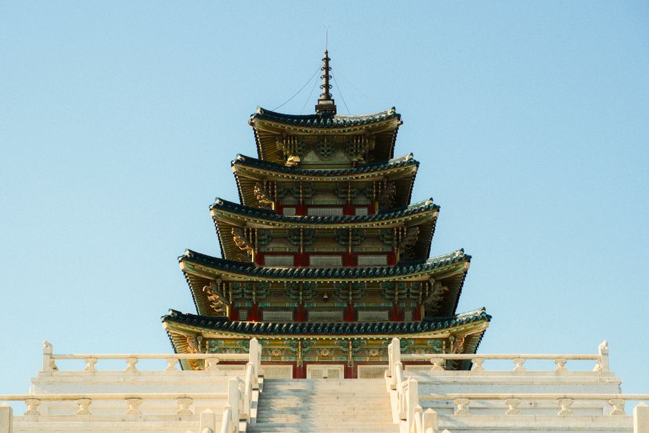 A traditional Korean pagoda tower with intricate details captured against a clear blue sky.