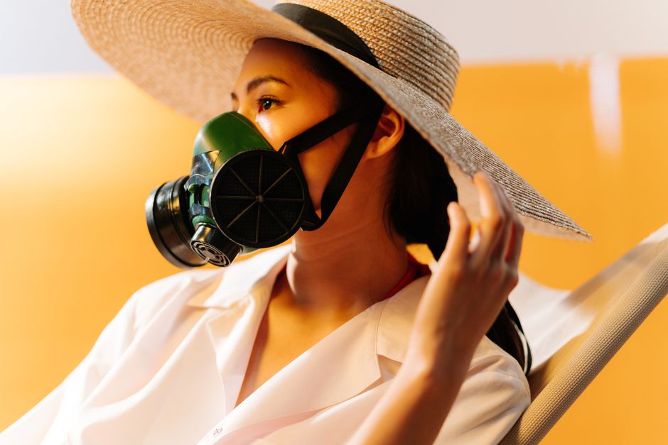 Portrait of a woman in a straw hat wearing a respirator, emphasizing climate change awareness.
