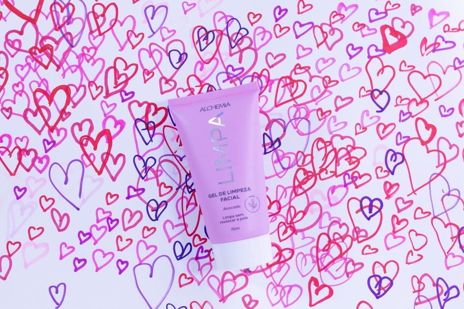 Pink facial cleansing gel tube surrounded by colorful heart doodles on white background.