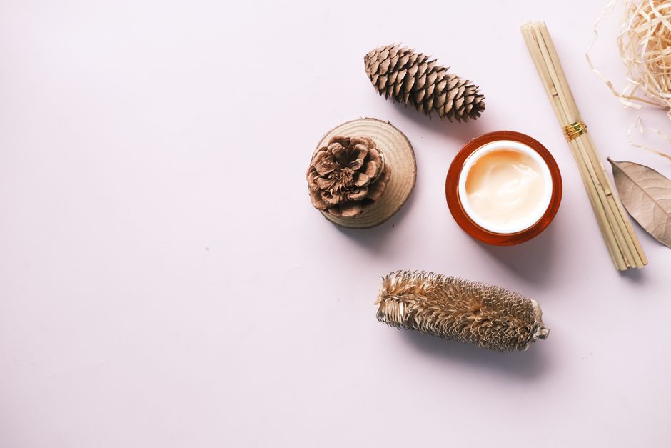 Top view of a skincare cream jar surrounded by natural elements on a studio background.