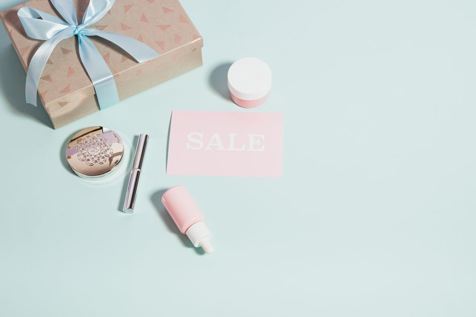 Stylish arrangement of beauty products with a sale card on a pastel background, perfect for promotional use.