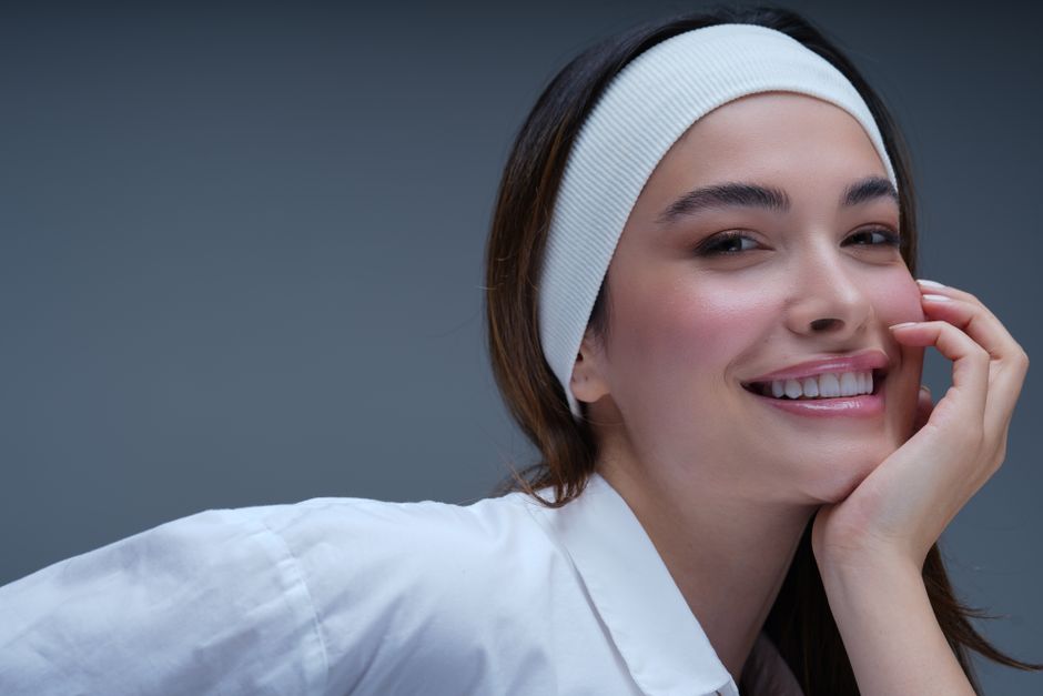 A confident woman smiling while wearing a white headband, conveying positivity and beauty.
